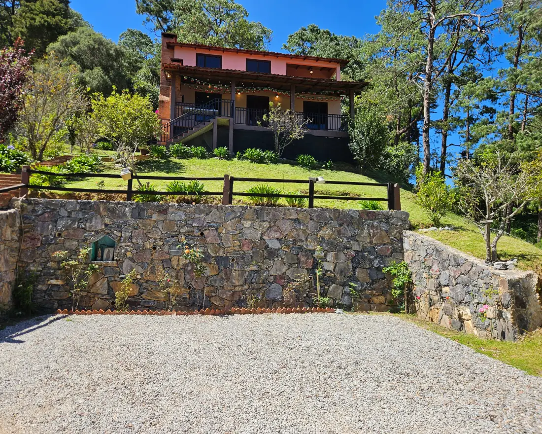 La cabaña vista desde el estacionamiento, sobre el muro de piedra