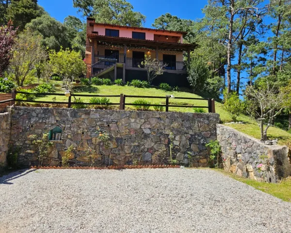 La cabaña desde el estacionamiento, sobre el muro de piedra